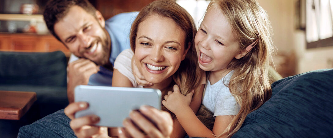 famille allongée sur le canapé en regardant une série sur le téléphone portable