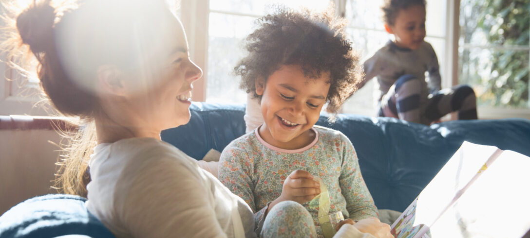 mère racontant une histoire à ses enfants assis sur le canapé en souriant