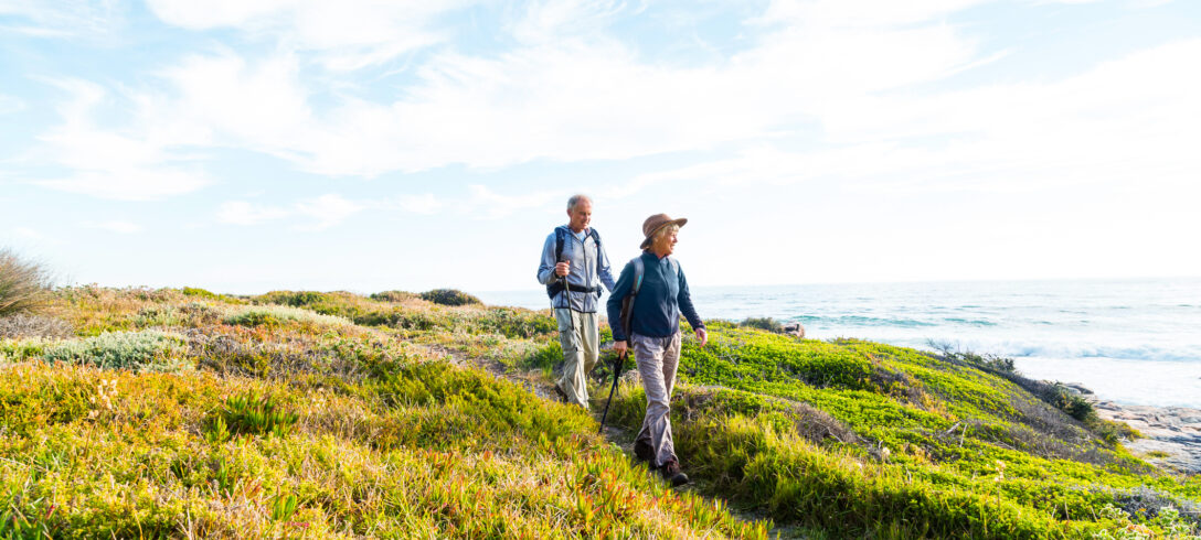 couple de personnes âgées se promenant le long des dunes d'une plage