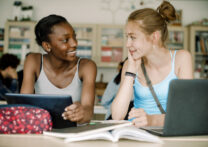 Adolescents souriants parlant assis à table dans la salle de classe