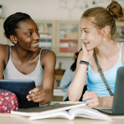 Adolescents souriants parlant assis à table dans la salle de classe