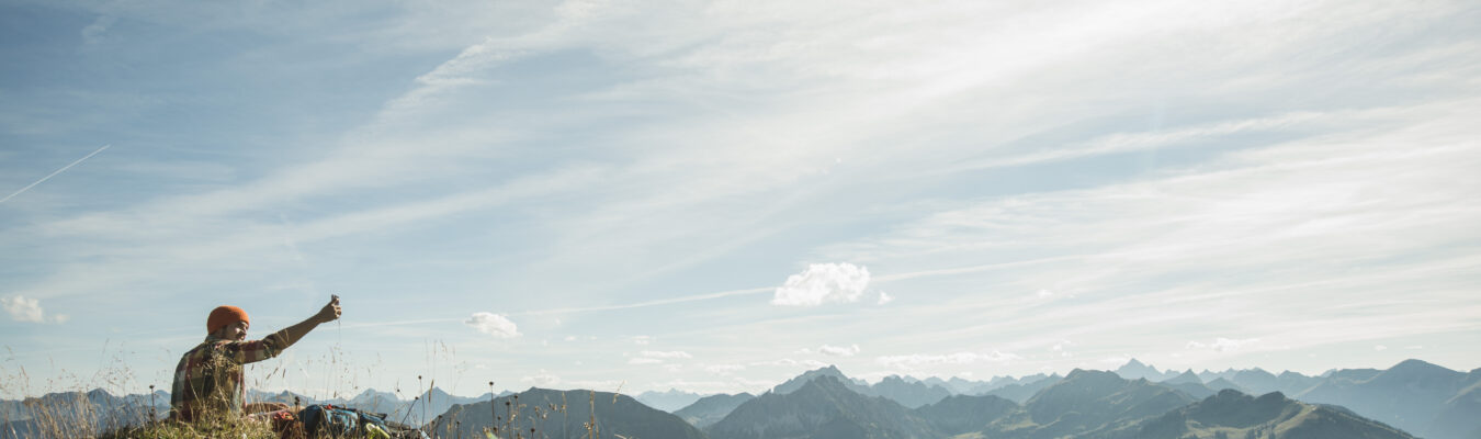 Autriche, Tyrol, Tannheimer Tal, jeune homme prenant en selfies mountainscape