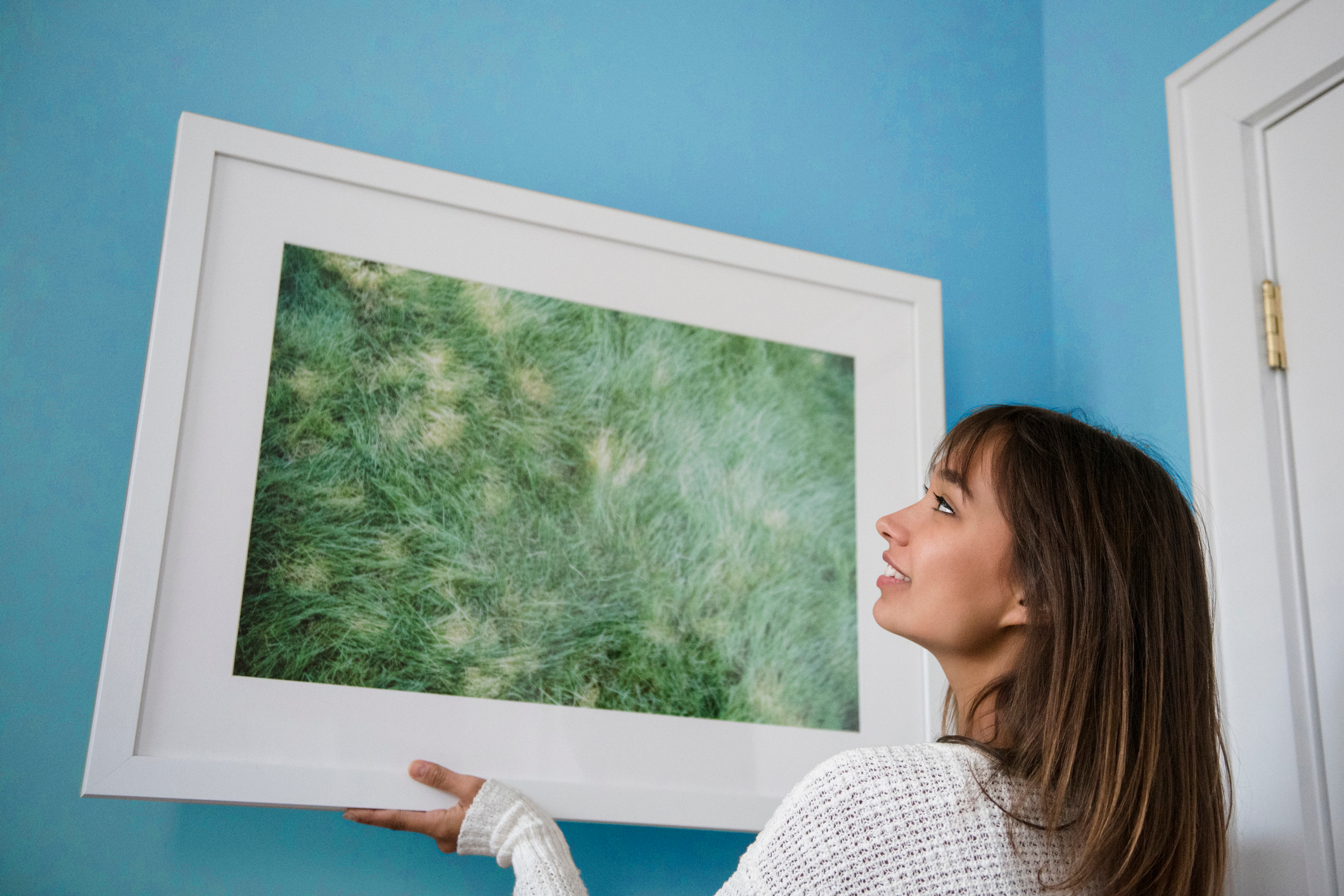 une jeune femme accrochant une photo au mur à la maison