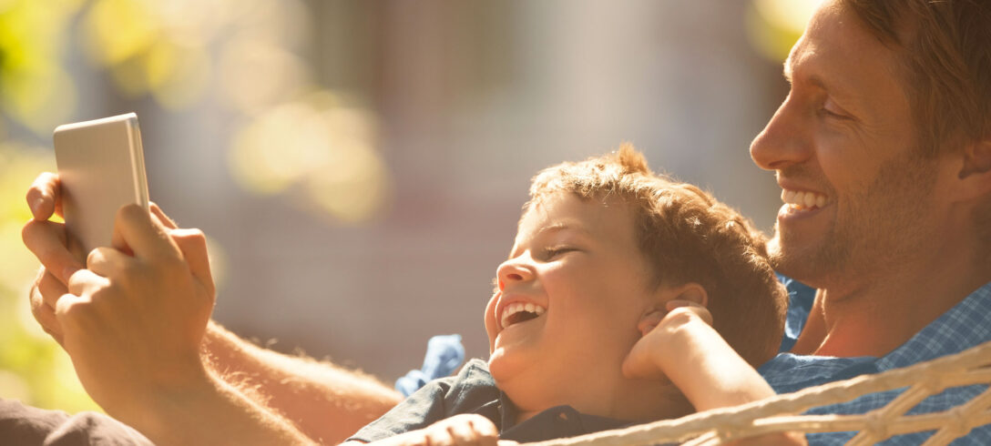 père avec son enfant devant smartphone