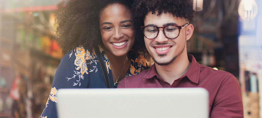 deux jeunes souriant à l'ordinateur portable