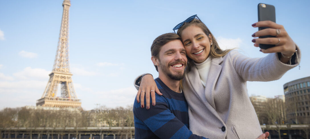 Un jeune couple visite Paris et prend des selfies devant les monuments de Paris