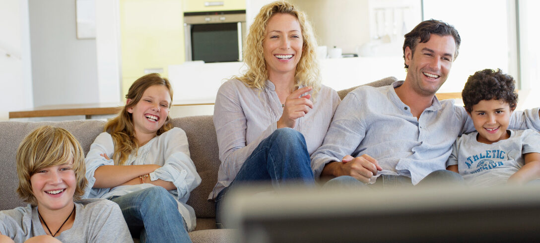 famille assise sur le canapé devant la télé
