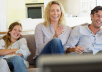 famille assise sur le canapé devant la télé